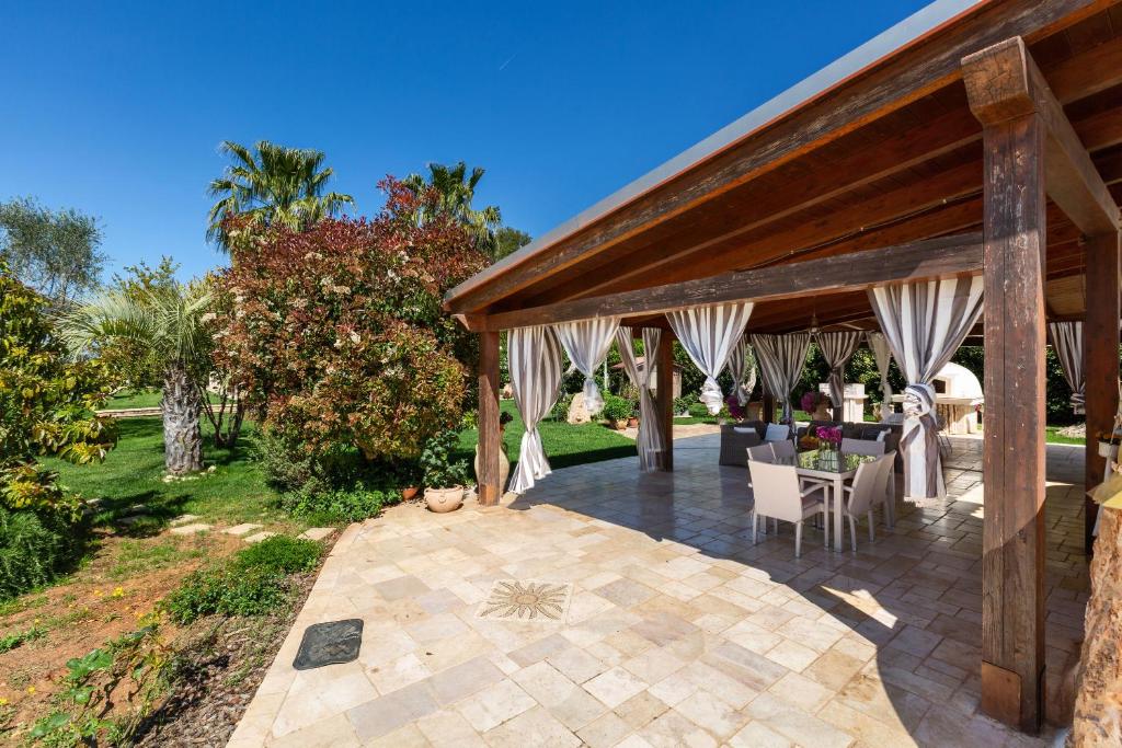 - un pavillon avec des rideaux blancs, une table et des chaises dans l'établissement Tenuta Bouganville by Perle di Puglia, à Francavilla Fontana