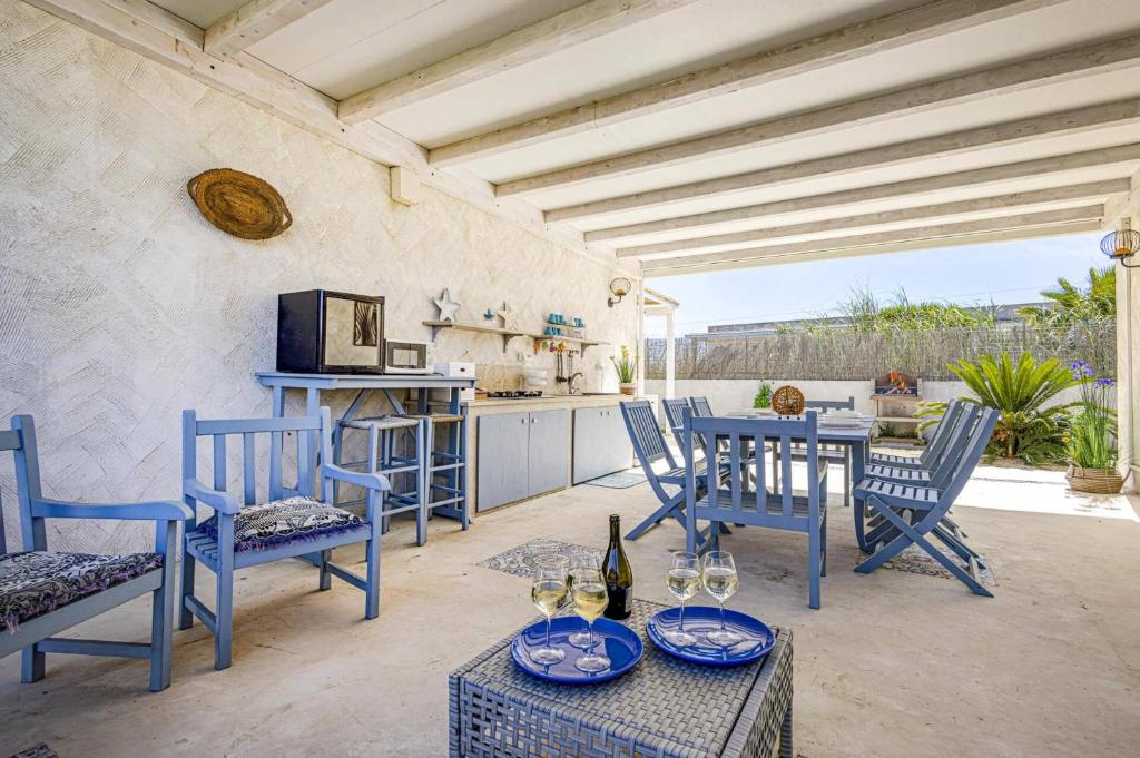 une terrasse avec des chaises bleues et une table avec des verres à vin dans l'établissement Villa Rosso Blu by Villa Plus, à Santa Maria Del Focallo
