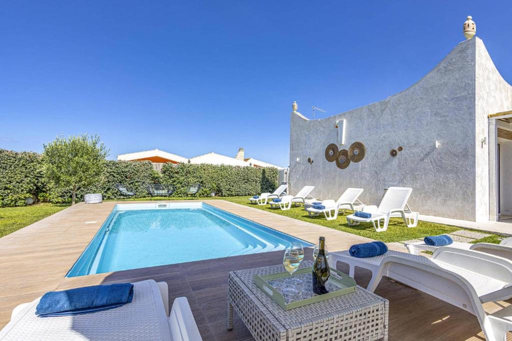 Cette villa dispose d'une piscine avec des chaises blanches. dans l'établissement Villa Rosso Blu by Villa Plus, à Santa Maria Del Focallo
