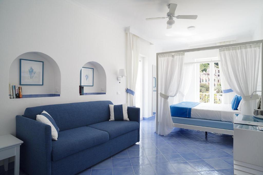 - un salon avec un canapé bleu et un lit dans l'établissement Hotel Aurora, à Sperlonga