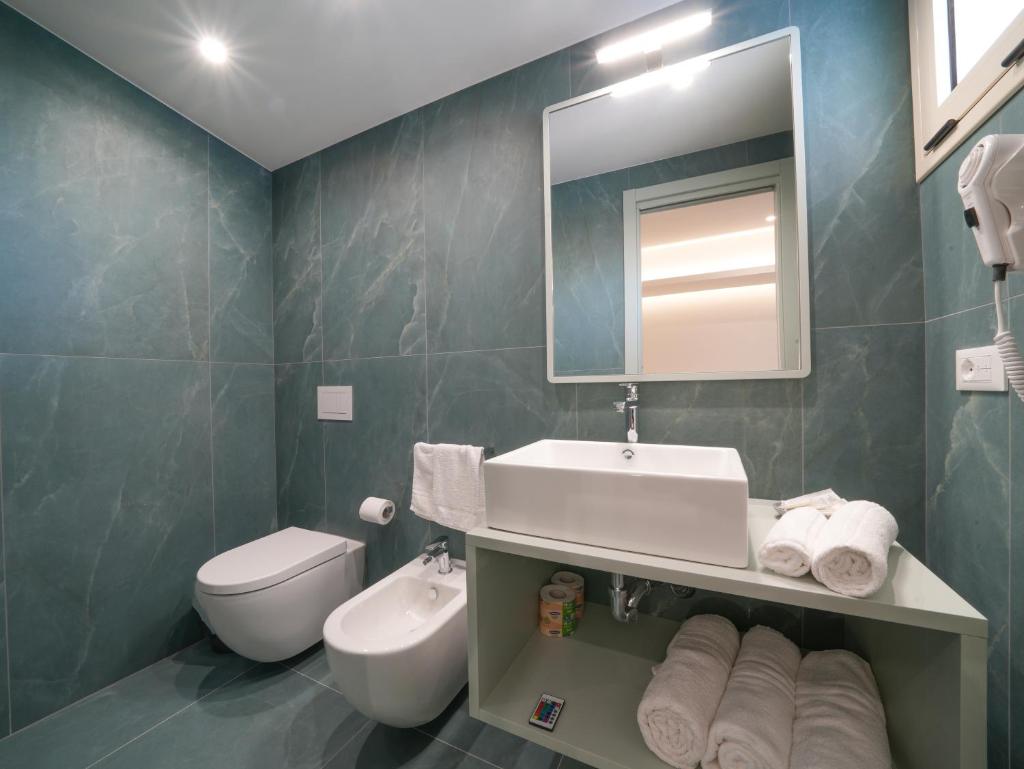 une salle de bain avec un lavabo, des toilettes et un miroir dans l'établissement Hotel MARINELLA - Private Free Parking - Grotticelle Beach 200 m, à Capo Vaticano
