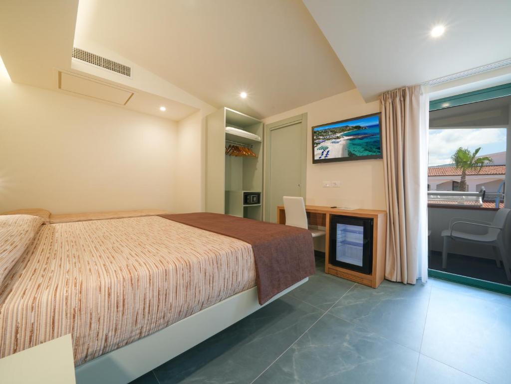 une chambre avec un lit et une télévision à écran plat dans l'établissement Hotel MARINELLA - Private Free Parking - Grotticelle Beach 200 m, à Capo Vaticano