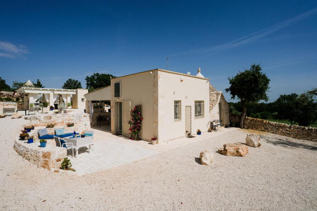 une maison avec un patio et des chaises dans le sable dans l'établissement Trullo del Benessere, à Martina Franca