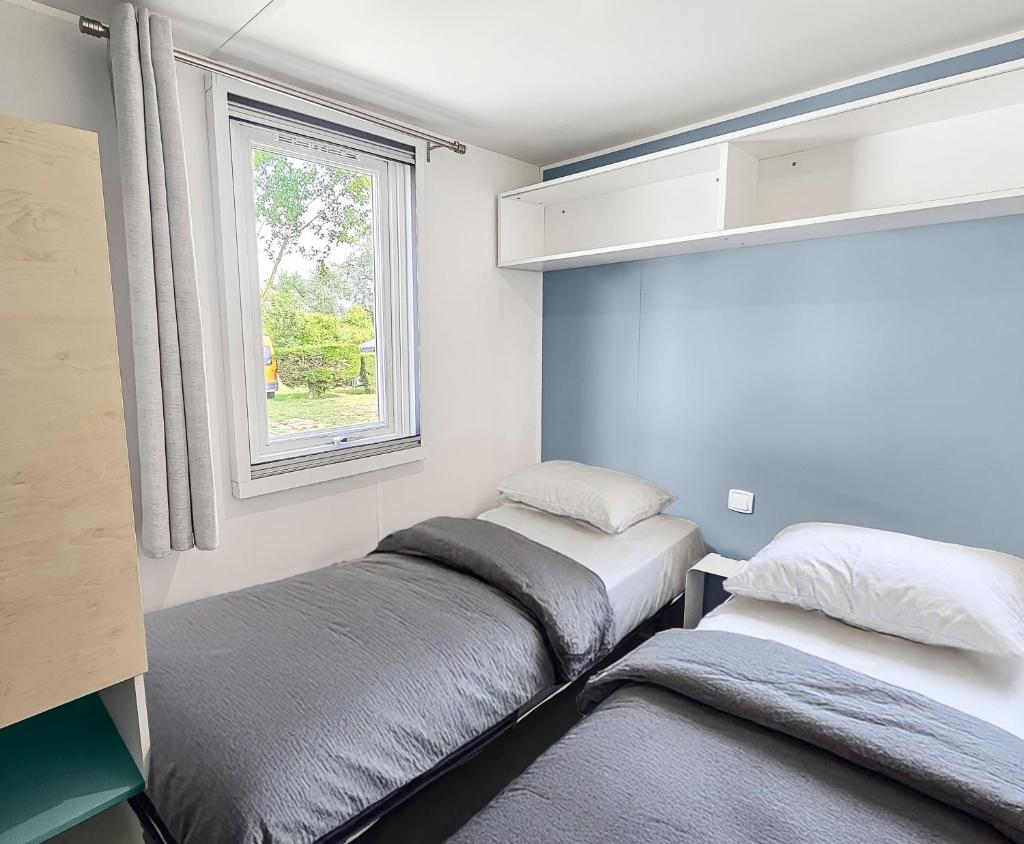 deux lits dans une petite pièce avec une fenêtre dans l'établissement Camping Riva Bella, à Ouistreham 24 autres photos