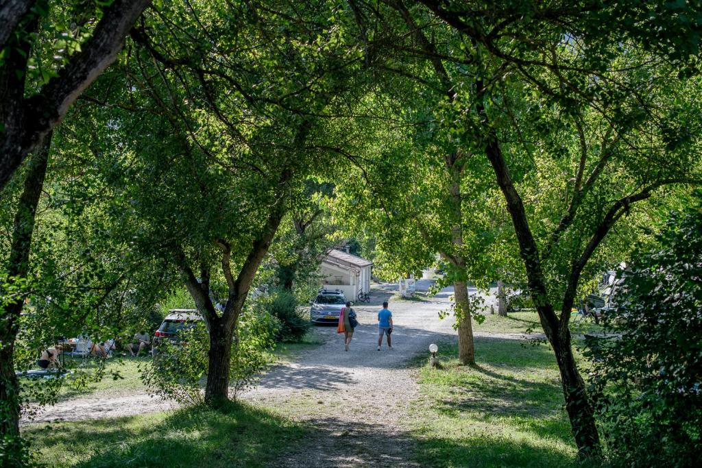 un groupe de personnes marchant sur un chemin de terre avec des arbres dans l'établissement Camping Onlycamp Les Tuillères, à Vercheny 19 autres photos
