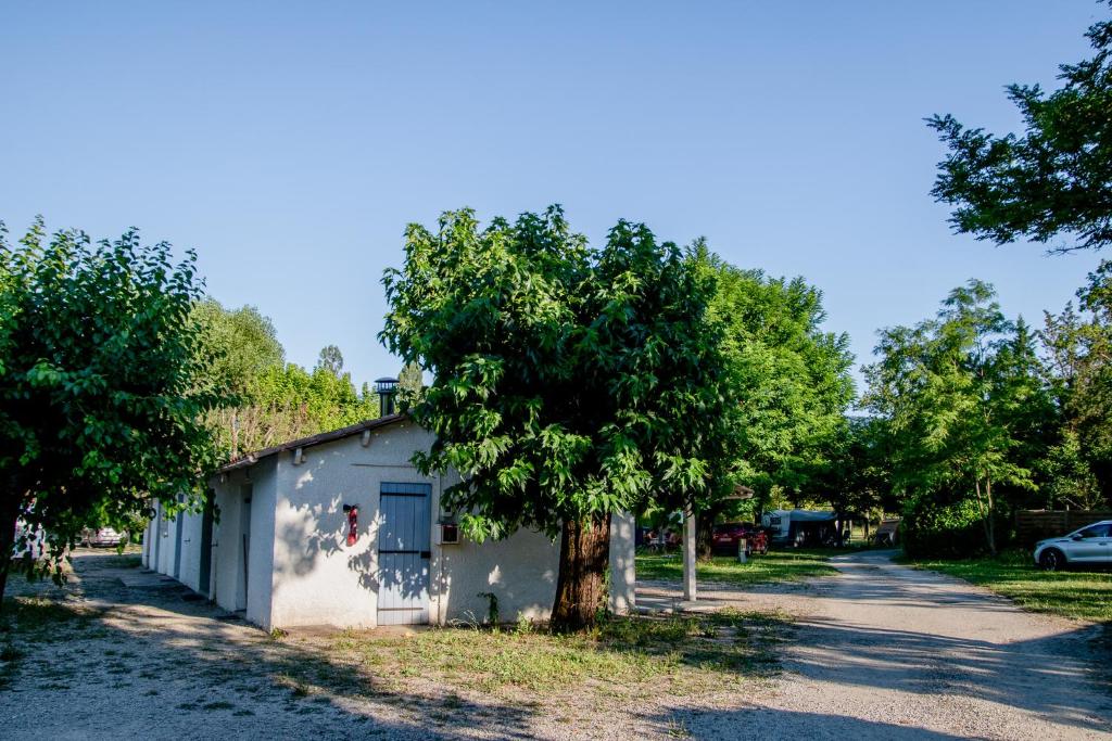un arbre devant un bâtiment blanc dans l'établissement Camping Onlycamp Les Tuillères, à Vercheny