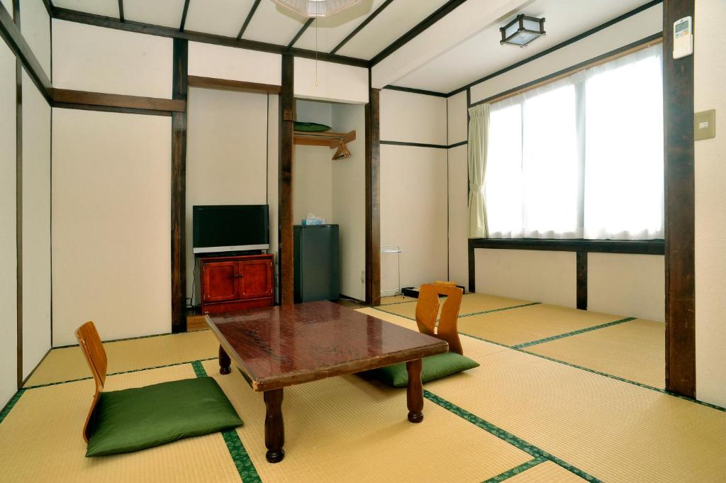 un salon avec une table et des chaises en bois dans l'établissement Ryokan Seifuso, à Matsumoto