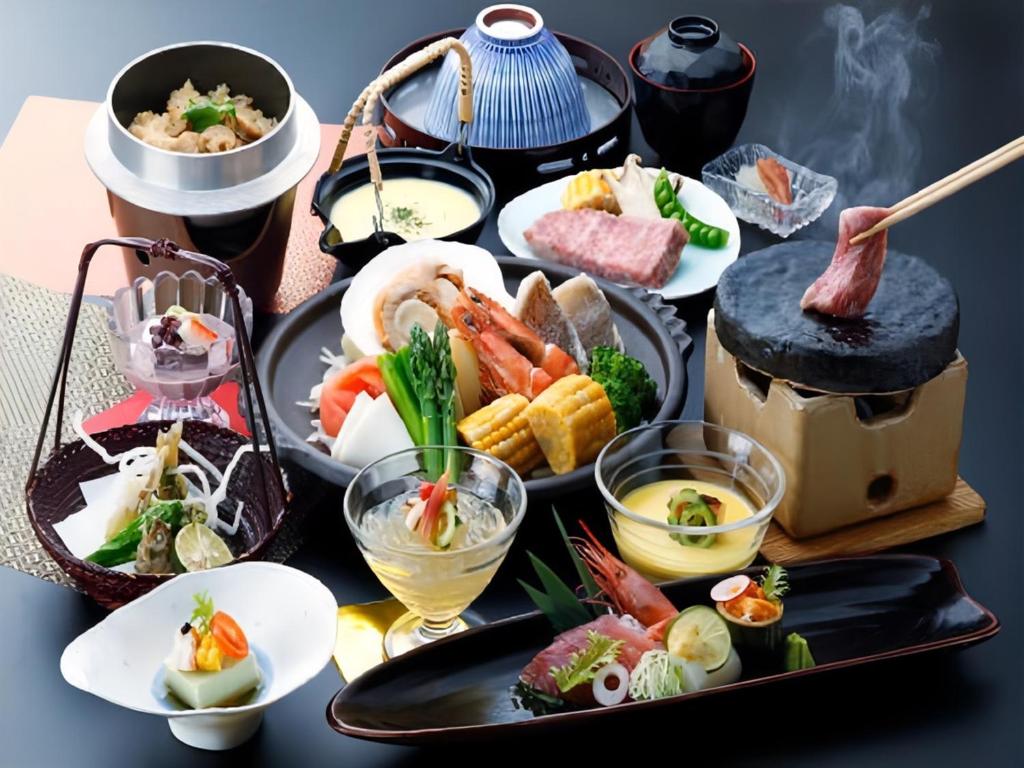 une table garnie de différents types d'aliments dans des assiettes dans l'établissement Livemax Resort Yuhigaura Kitu Onsen, à Kyōtango