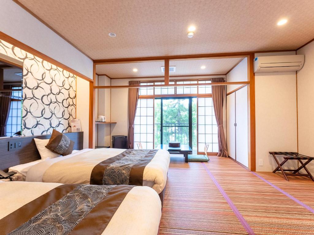 une chambre d'hôtel avec deux lits et une grande fenêtre dans l'établissement Livemax Resort Yuhigaura Kitu Onsen, à Kyōtango