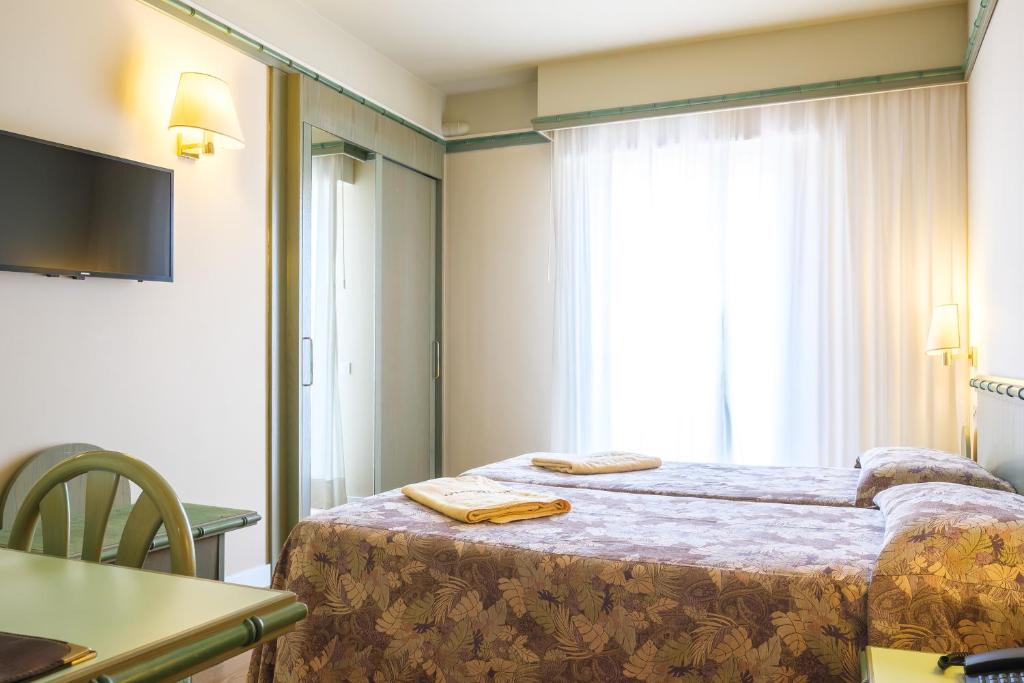une chambre d'hôtel avec deux lits et une fenêtre dans l'établissement Hotel Montecarlo, à Lido di Jesolo
