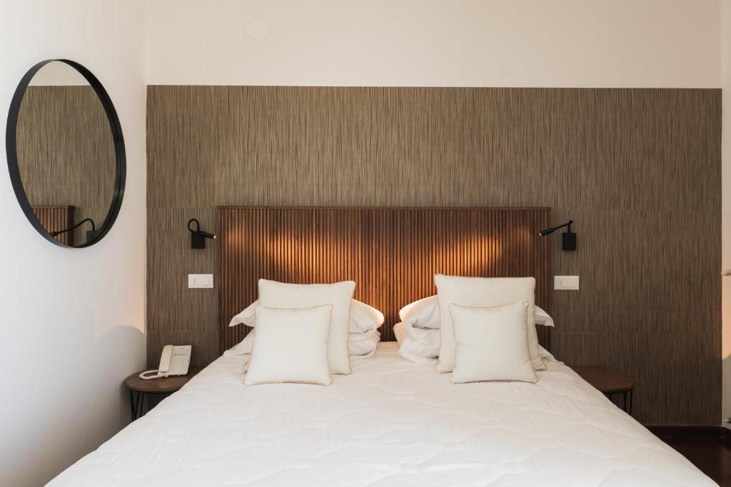 - une chambre avec un lit doté d'oreillers blancs et d'un miroir dans l'établissement HR Resort, à Senigallia