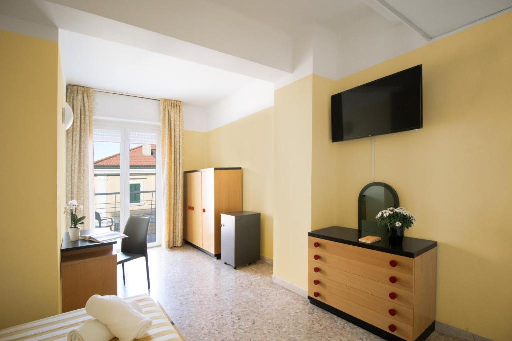 une chambre avec un lit, un bureau et une télévision fixée au mur dans l'établissement Hotel Marcelli, à Numana