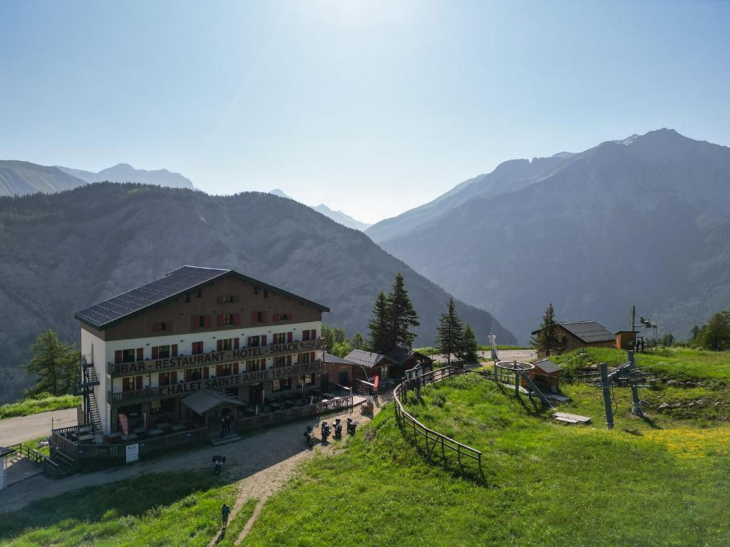 un bâtiment sur une colline avec des montagnes en arrière-plan dans l'établissement Chalet Sainte Anne, à Condamine-Châtelard