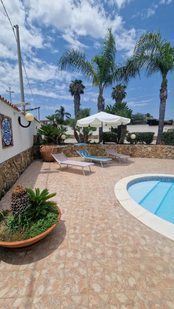 un complexe avec piscine et palmiers dans l'établissement Villa CARLOTTA, à Brucoli