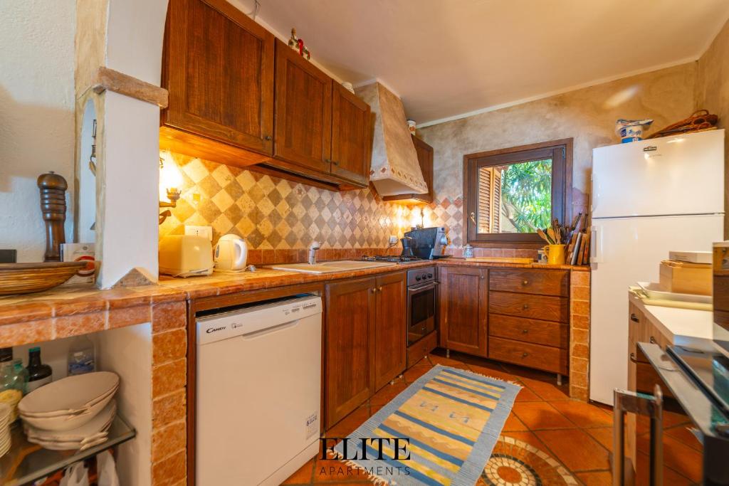 une cuisine avec des armoires en bois et un réfrigérateur blanc dans l'établissement Villa sul Golfo del Pevero con accesso a mare, à Porto Cervo