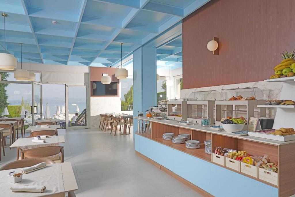 un restaurant avec une ligne de buffet avec des tables et des chaises dans l'établissement Hotel Unico by Dori, à Sirmione