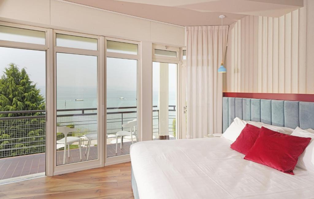 une chambre avec un lit avec des oreillers rouges et un balcon dans l'établissement Hotel Unico by Dori, à Sirmione