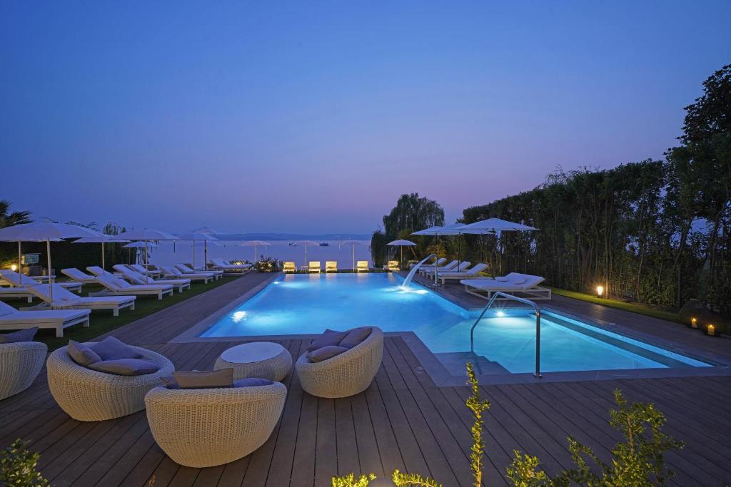 une piscine avec des chaises longues et un complexe hôtelier dans l'établissement Hotel Unico by Dori, à Sirmione