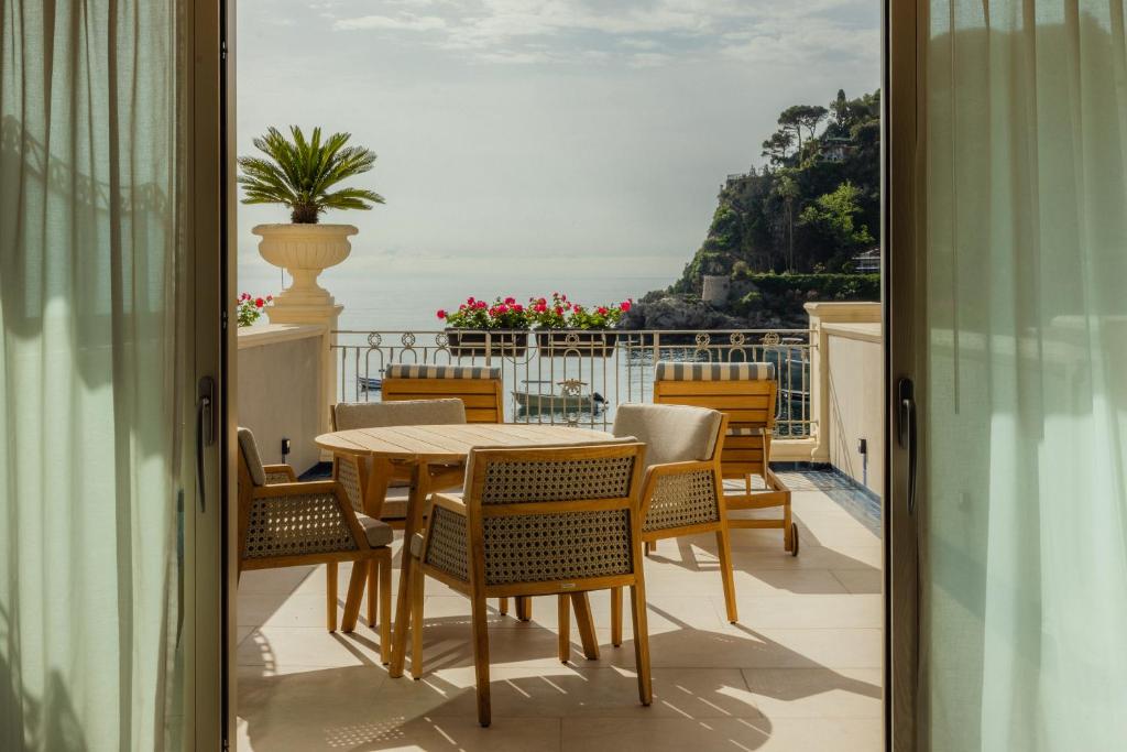 une table et des chaises sur un balcon avec vue sur l'océan dans l'établissement Mazzarò Sea Palace - The Leading Hotels of the World, à Taormine