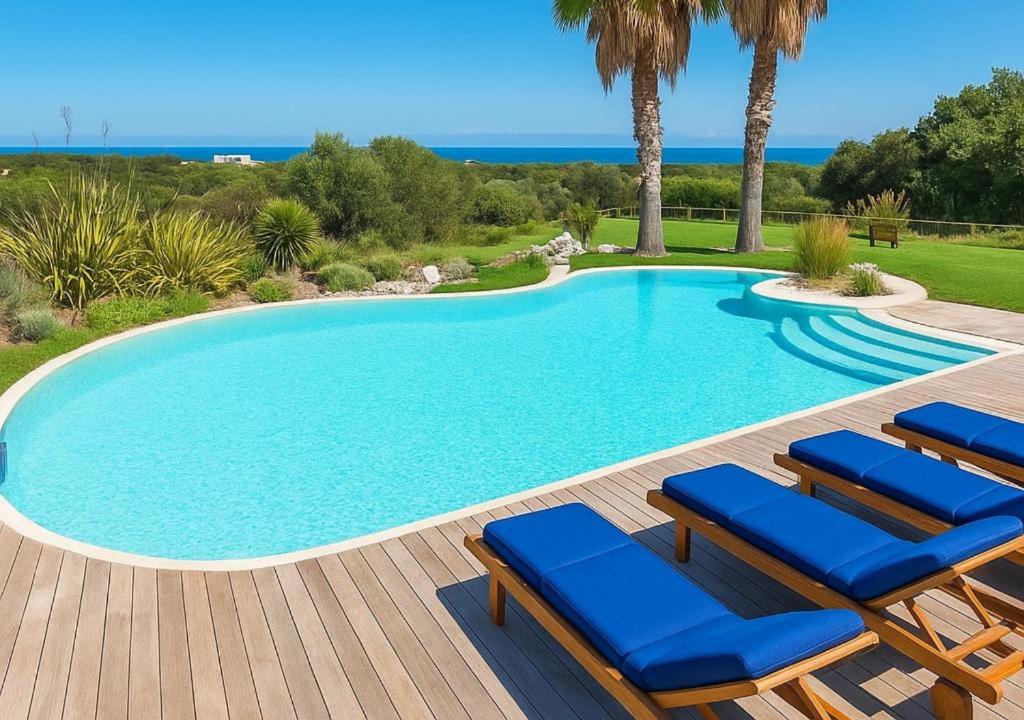 une piscine avec des chaises longues sur une terrasse en bois dans l'établissement Villa Flavia, à Polignano a Mare