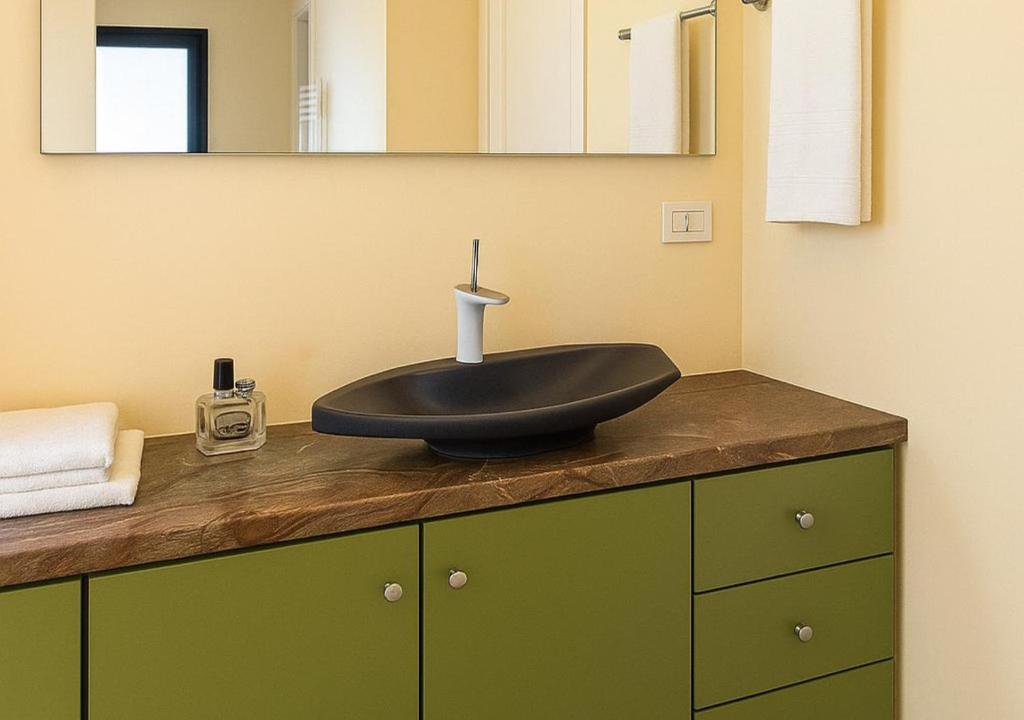 La salle de bains est pourvue d'un lavabo noir sur le comptoir. dans l'établissement Villa Flavia, à Polignano a Mare