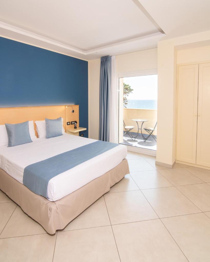 une chambre avec un grand lit et une vue sur l'océan dans l'établissement Grand Hotel Santa Maria, à Santa Maria di Castellabate