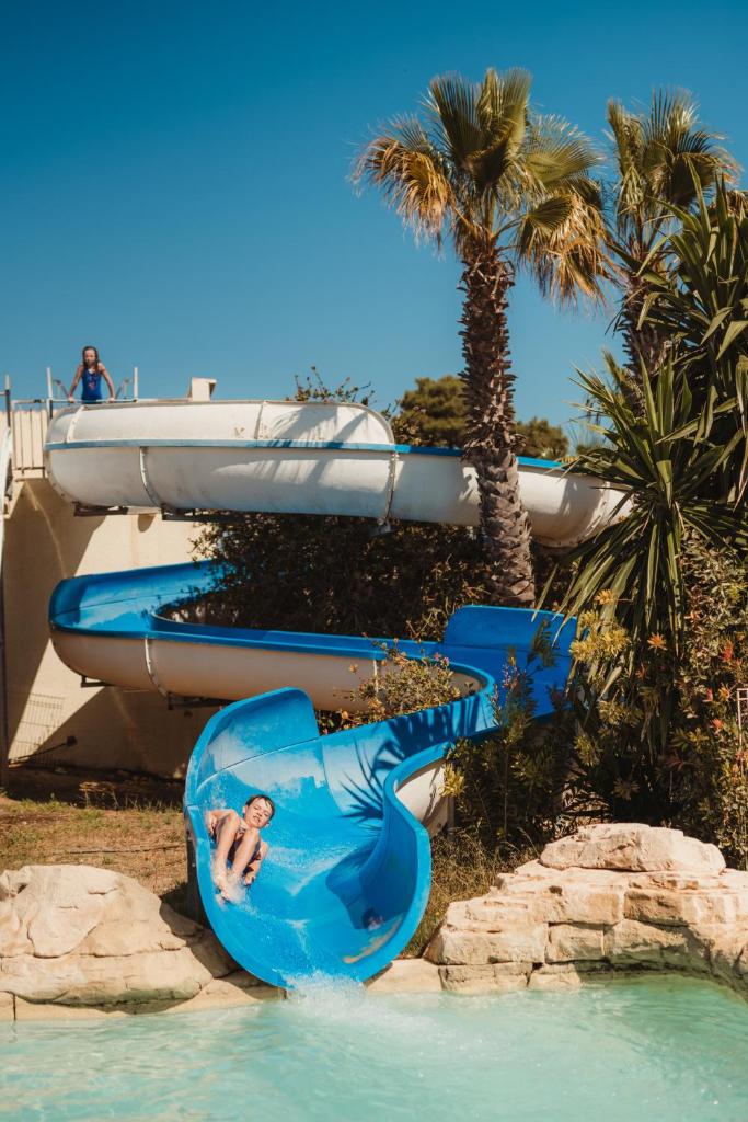 une personne utilisant un toboggan aquatique dans un parc aquatique dans l'établissement Domaine Les Mûriers, à Vendres-Plage
