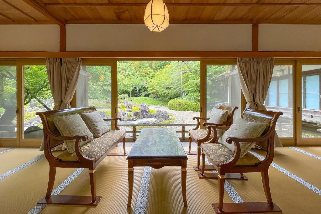 un salon avec des chaises, une table et des fenêtres dans l'établissement 高野山 宿坊 総持院 -Koyasan Shukubo Sojiin-, à Koyasan