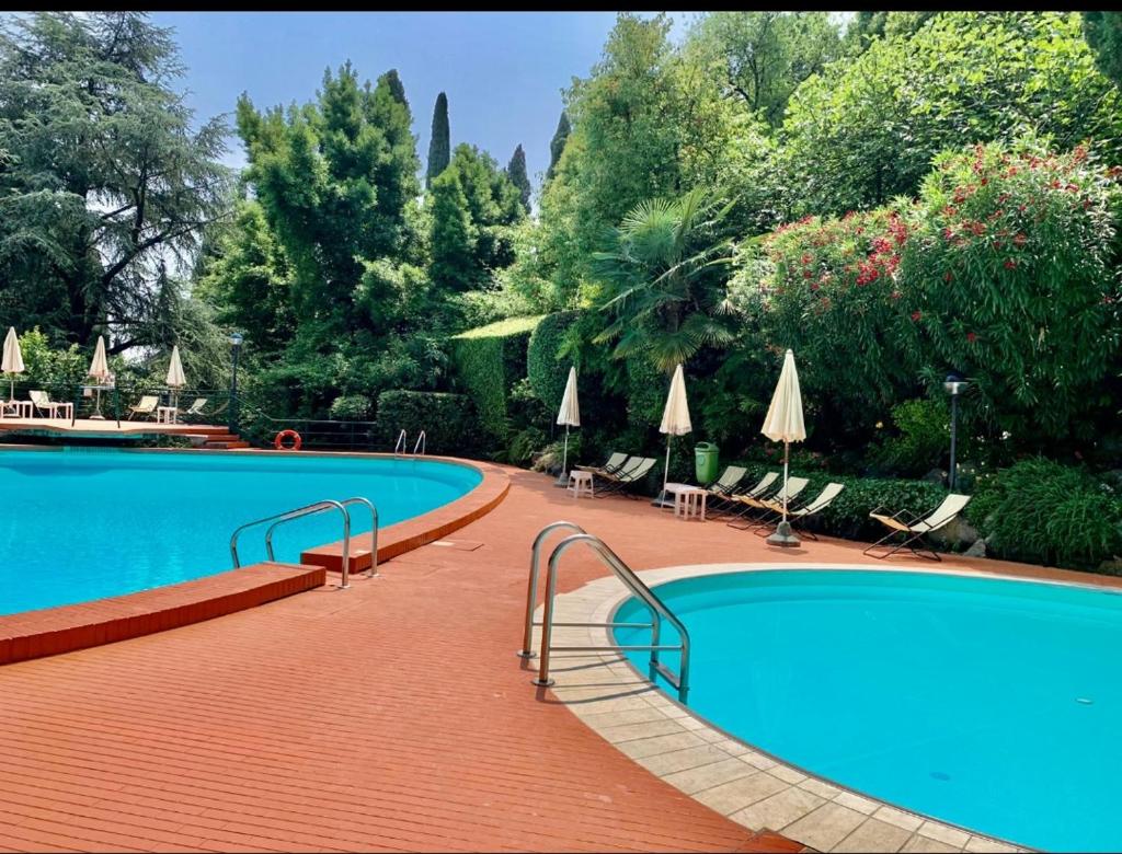 une grande piscine avec chaises et parasols dans l'établissement Residence Villa Alba room nr 415, à Gardone Riviera