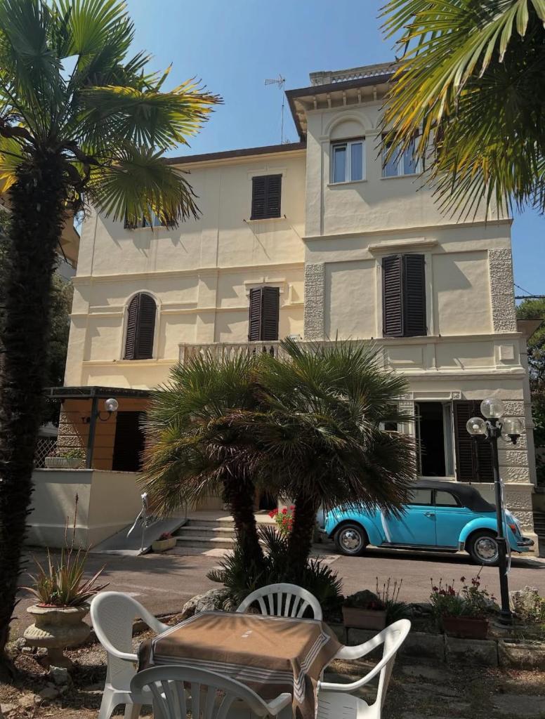une voiture bleue garée devant un bâtiment dans l'établissement Hotel VILLA PINA, à Senigallia