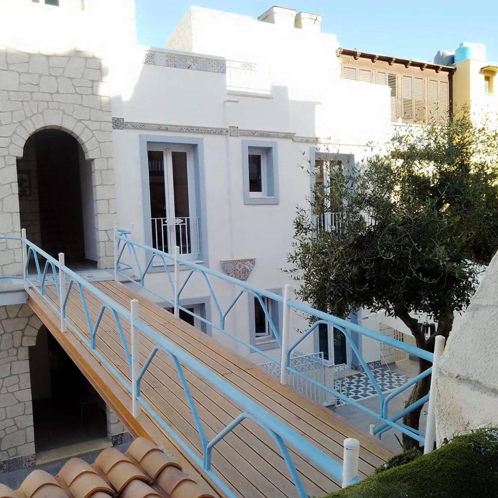 un escalier menant à un bâtiment blanc avec une rampe bleue dans l'établissement RESINDENZE Donna Sabella, à Santa Flavia