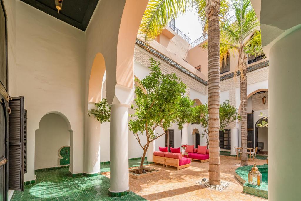 un hall avec des palmiers et des meubles roses dans l'établissement Riad Akasia, à Marrakech