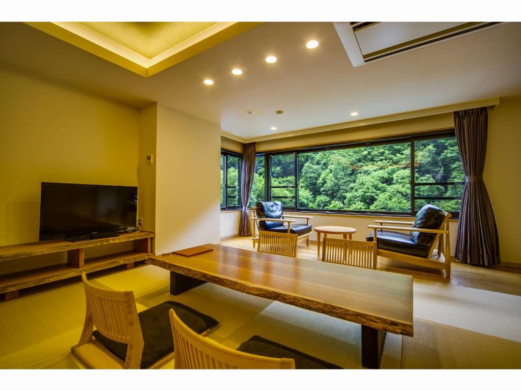 un salon avec une table et une grande fenêtre dans l'établissement Hotel Okuyumoto, à Hakone