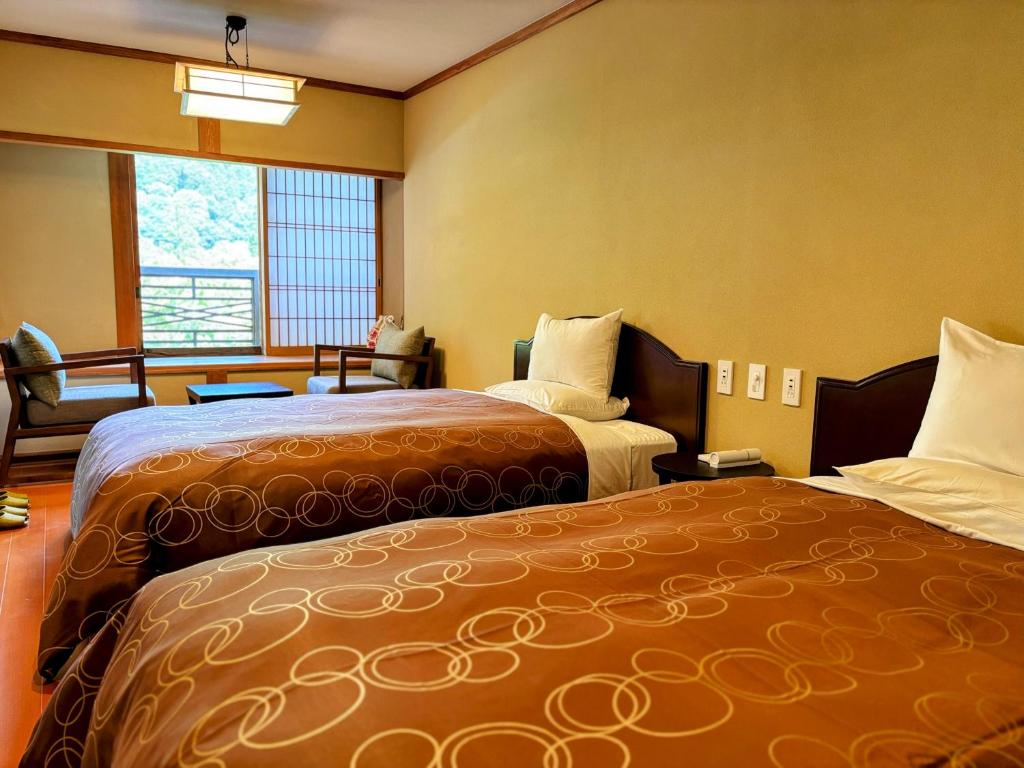 une chambre d'hôtel avec deux lits et une fenêtre dans l'établissement Yufuin Santoukan, à Yufu 62 autres photos