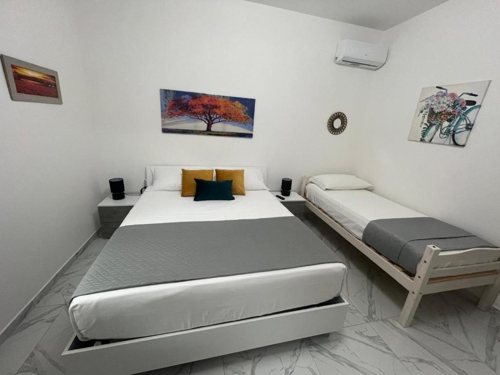 deux lits dans une chambre aux murs blancs dans l'établissement Villa Grazia, à SantʼAgata di Militello