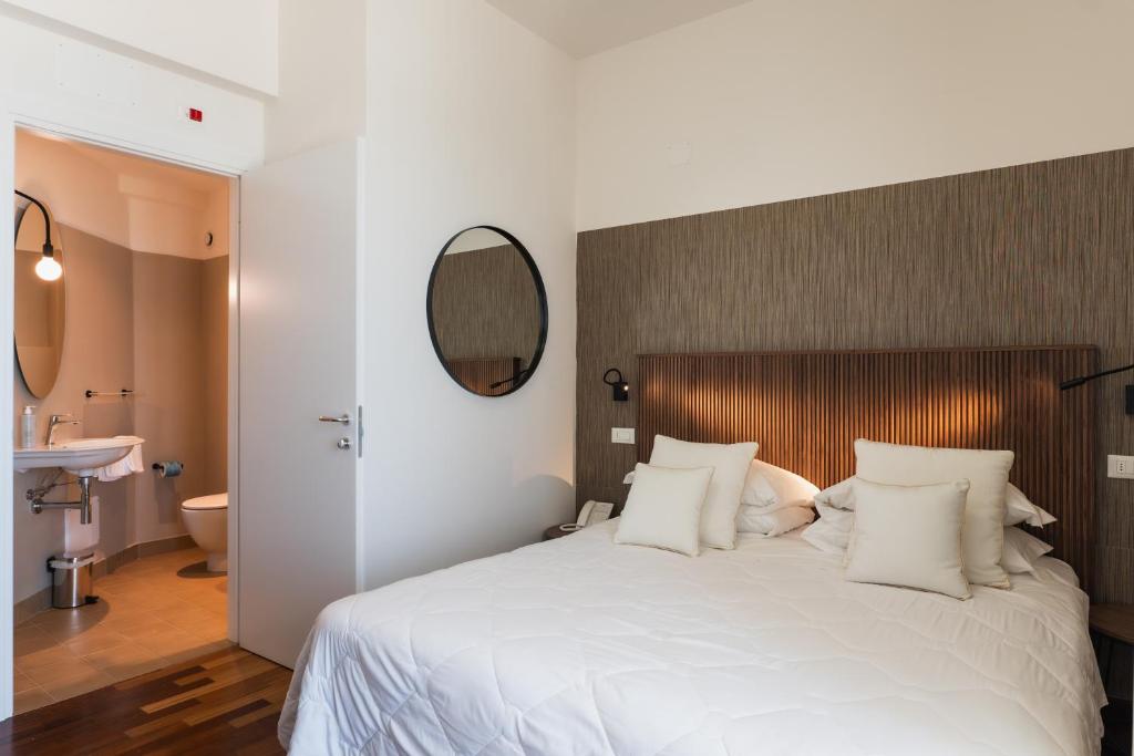 une chambre avec un grand lit blanc et un miroir dans l'établissement HR Resort, à Senigallia