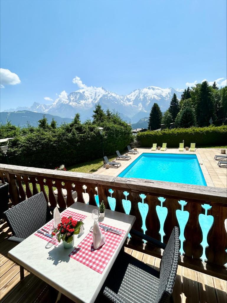d'une table et de chaises sur un balcon avec piscine. dans l'établissement Hôtel Arbois Bettex, à Saint-Gervais-les-Bains