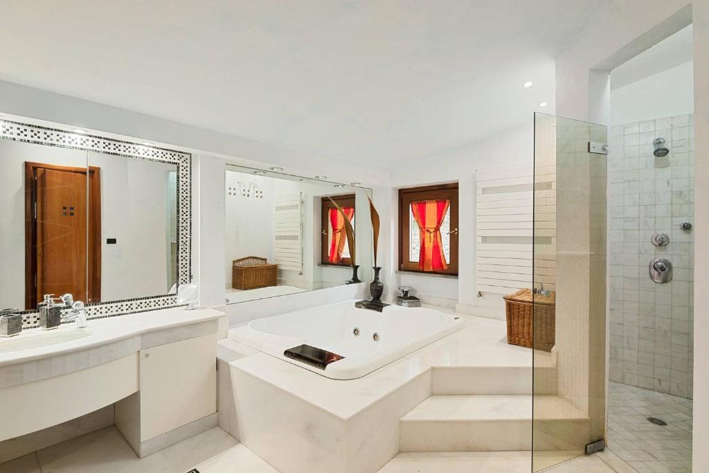 La salle de bains blanche est pourvue d'une baignoire, d'un lavabo et d'une douche. dans l'établissement Piccolo Paradiso, à Formia