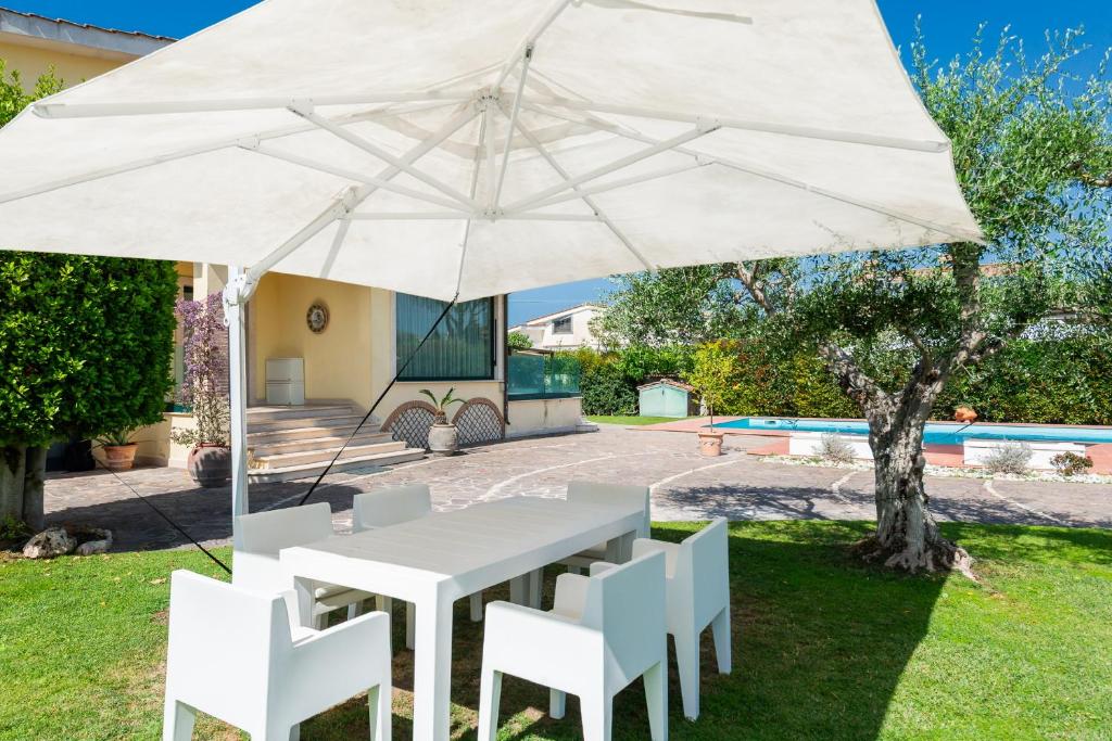 - une table et des chaises blanches sous un parasol dans la cour dans l'établissement Luxury Suite in Villa with Private Pool - Near Rome & Ostia, à Lido di Ostia