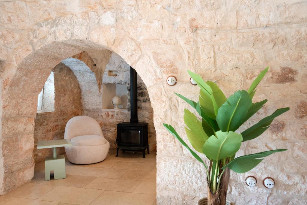 une pièce avec un mur en pierre avec une cheminée et une plante dans l'établissement Trullo Alba, à Cisternino