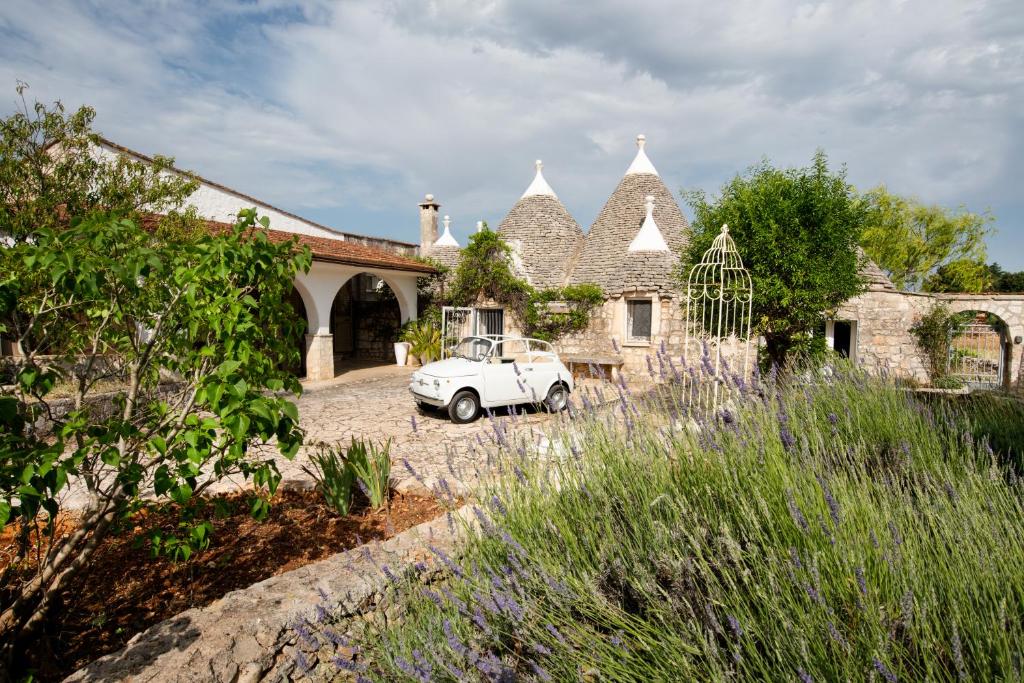 une voiture blanche garée devant une maison dans l'établissement Trullo Alba, à Cisternino