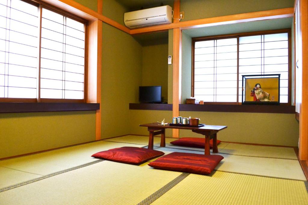une chambre avec une table et deux tapis rouges dans l'établissement Ryokan Matsumuraya, à Kawagoe