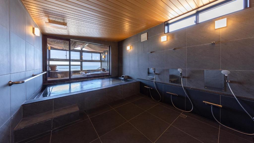 une salle de bain avec une baignoire et une fenêtre dans l'établissement YuhigauraOnsen Umi no Hana, à Kyōtango 31 autres photos