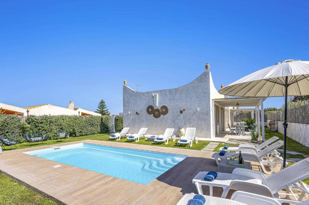 une maison dotée d'une piscine avec des chaises et un parasol dans l'établissement Villa Rosso Blu by Villa Plus, à Santa Maria Del Focallo