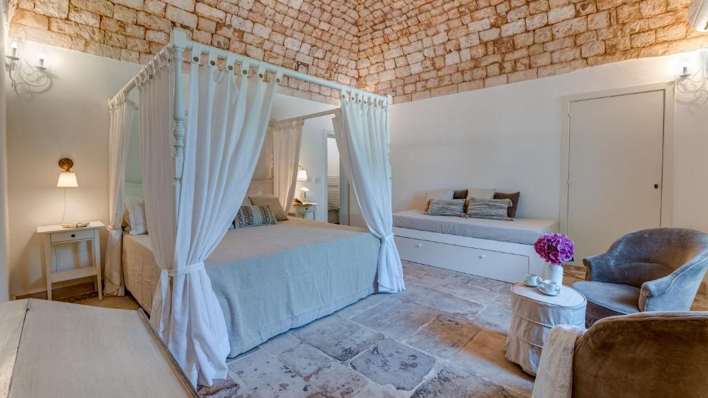 une chambre avec un lit à baldaquin et une chaise dans l'établissement Masseria Profilo 8, Emma Villas, à Monopoli
