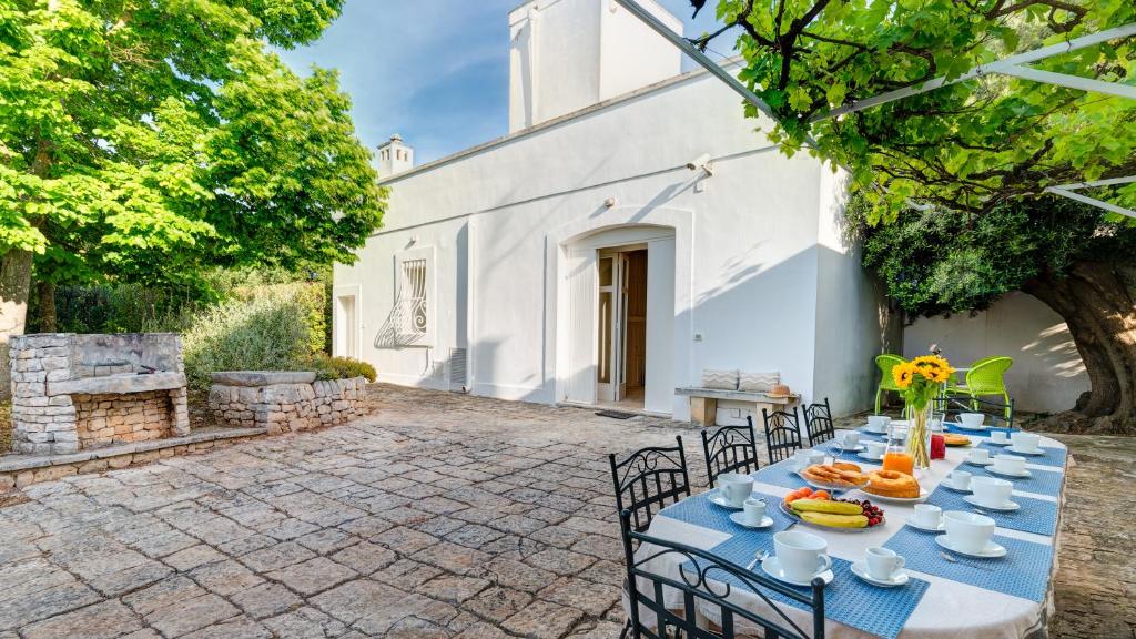 une table bleue avec des chaises dans une cour avec un bâtiment dans l'établissement Masseria Profilo 8, Emma Villas, à Monopoli