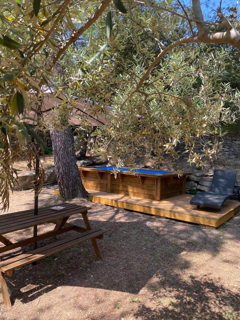 une table de pique-nique et un banc sous un arbre dans l'établissement Bungalow cosy varois avec piscine soleil calme et nature, à Pourrières