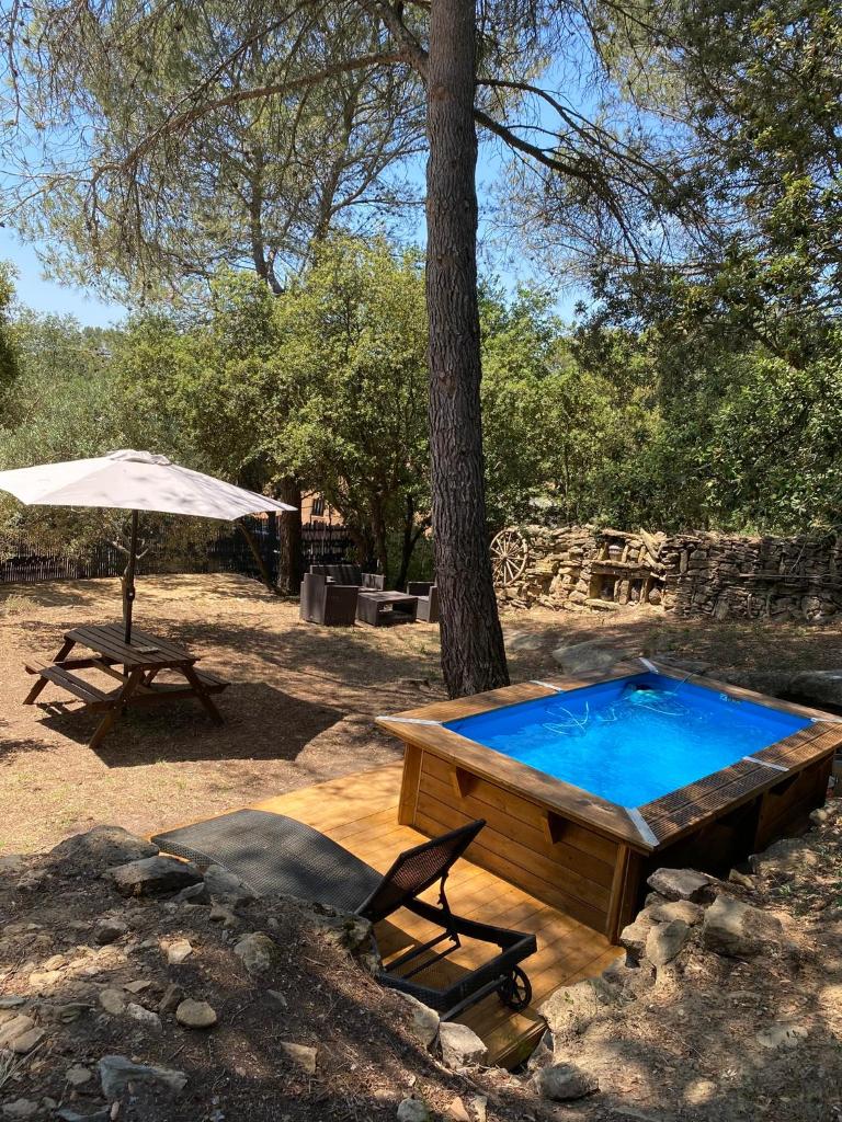 une piscine et une table de pique-nique et un parasol dans l'établissement Bungalow cosy varois avec piscine soleil calme et nature, à Pourrières