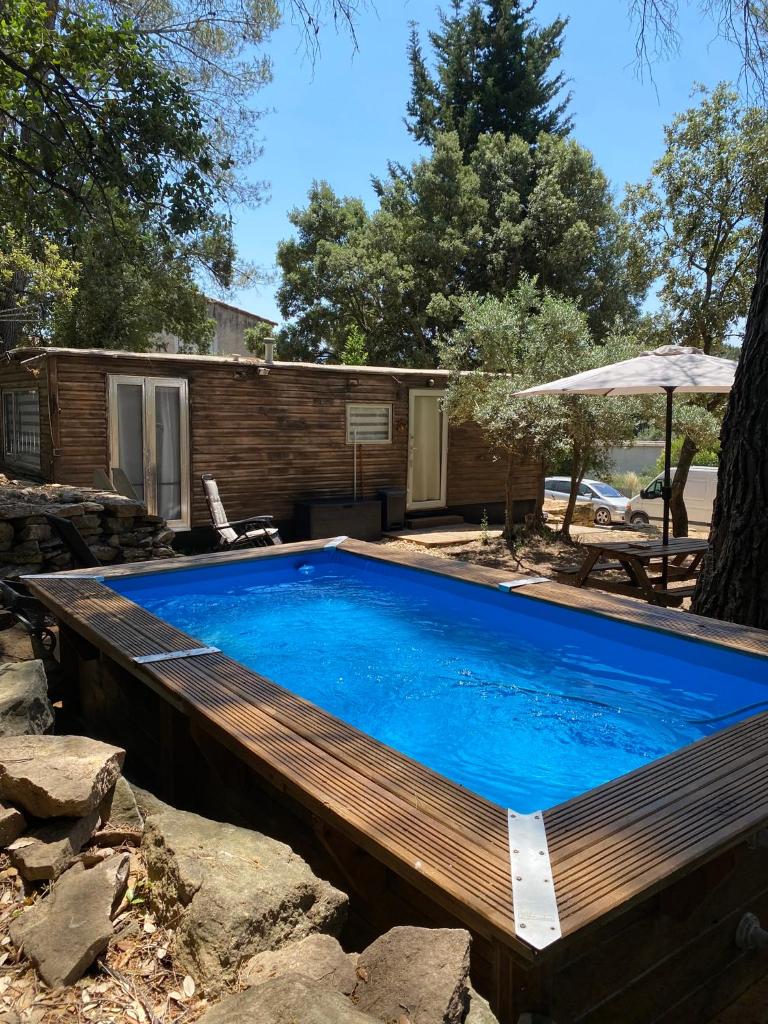 une grande piscine avec une terrasse en bois dans l'établissement Bungalow cosy varois avec piscine soleil calme et nature, à Pourrières
