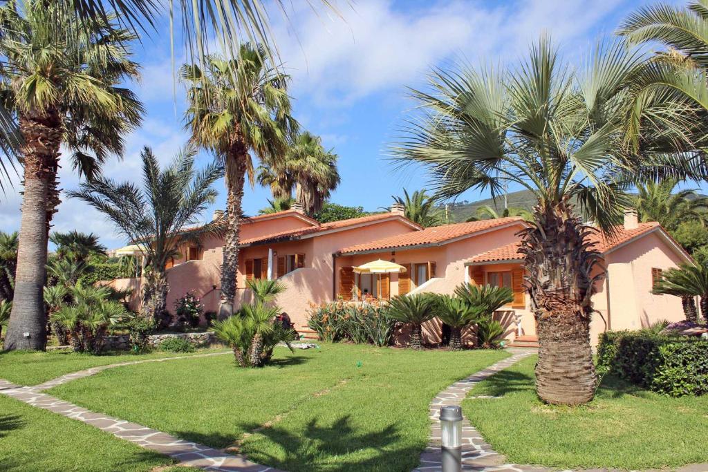 une maison avec des palmiers devant dans l'établissement Residence Cala dei Peducelli, à Capoliveri